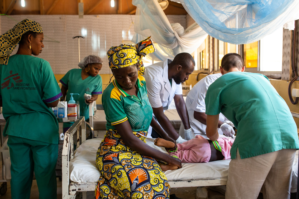 La madre de Warda Kaladjavai lo sostiene mientras los médicos le cambian las vendas. Warda tuvo un accidente de motocicleta en Maroua y ella lo llevó directamente al hospital.