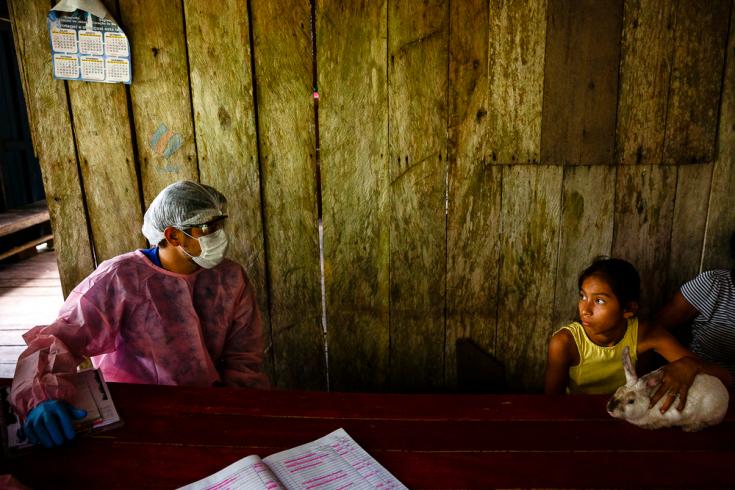 Un trabajador del sistema de salud municipal de Brasil habla con una familia durante las visitas a domicilio que se realizaron en la región del lago Mirini.