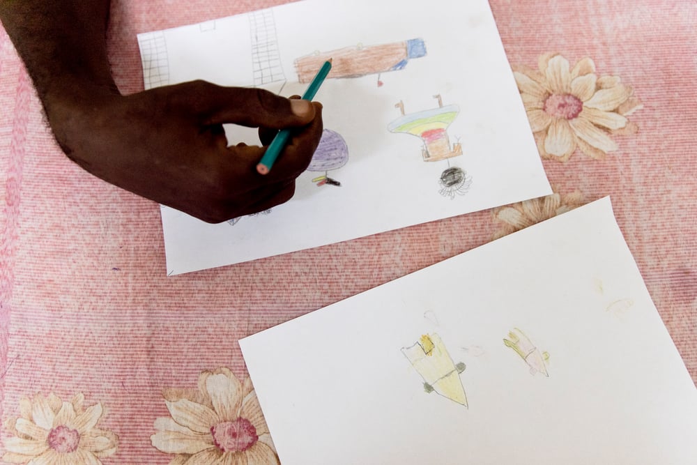 Aimé-Césaire Likosso, asesor de salud mental, señala detalles en algunos dibujos hechos por niños y niñas sobrevivientes de violencia sexual. República Centroafricana, noviembre de 2020.