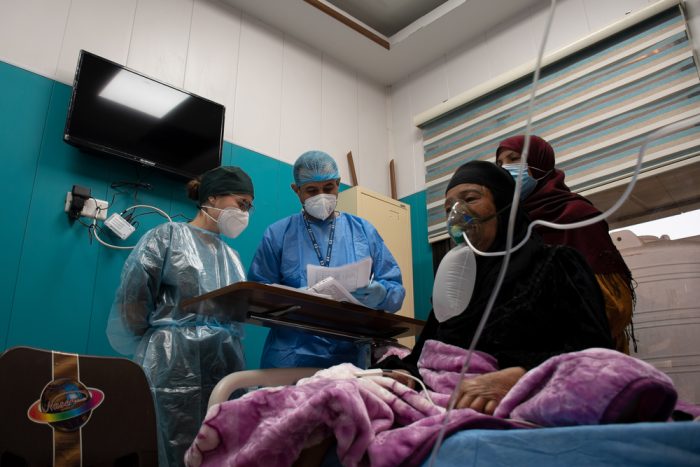 Una paciente de COVID-19 recibe oxígeno en la sala de hospitalización de MSF dentro del hospital al Kindi, en Bagdad. Las enfermeras de MSF revisan su condición y dan instrucciones al cuidador (su hijo) sobre cómo asistirla.
Hassan Kamal Al-Deen/MSF
