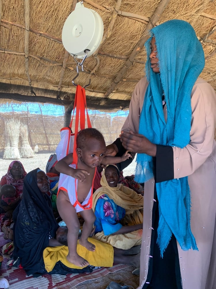 Nuestro equipo médico pesa a un niño con desnutrición en la clínica que instalamos en la aldea de Dilli. Sudán, abril de 2021
