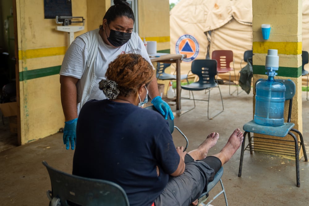 Nuestra enfermera Lucero escucha a una paciente que atravesó el Darién mientras ésta mantiene los pies en alto, antes de comenzar a curarlos. Panamá, junio de 2021