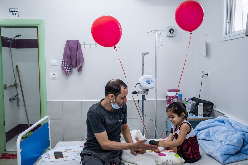 Hala ríe mientras habla por videollamada con su madre y sus hermanas, un día después de que los cirujanos de nuestra unidad de reconstrucción de extremidades del hospital Al-Awda le operaran el pie. Gaza, agosto de 2021