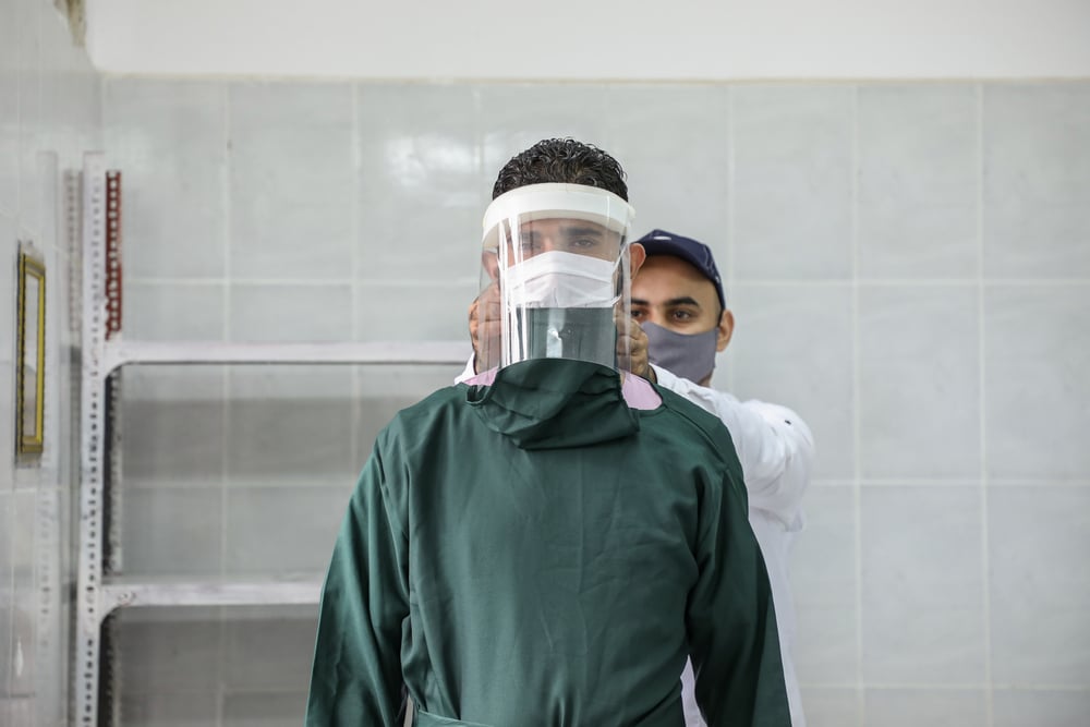 Uno de nuestros trabajadores le ajusta el equipo de protección contra el COVID-19 a otro en Al-Sahul, Yemen. Julio de 2020