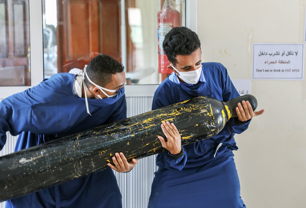 Dos trabajadores del centro Al-Sahul de COVID-19 están tratando de trasladar una botella de oxígeno al interior de la Unidad de Cuidados Intensivos. Yemen, julio de 2020