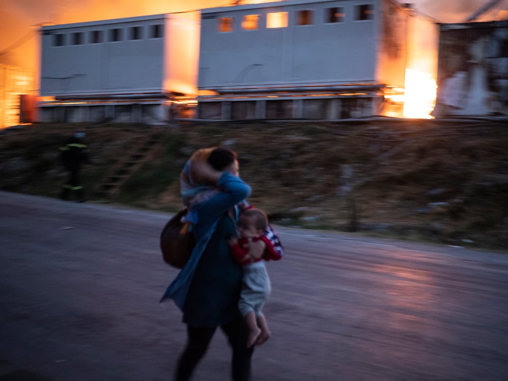 Una mujer escapa con su bebé de los incendios en el campo de Moria, el 9 de septiembre de 2020. Isla de Lesbos, Grecia