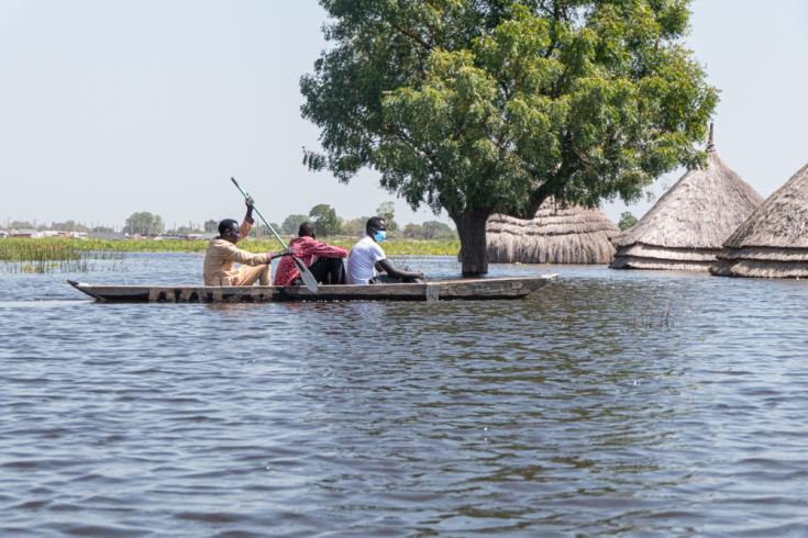 Hombres en una canoa navegando, donde los hogares, instalaciones sanitarias, escuelas y mercados están completamente inundados. Sudán del Sur.