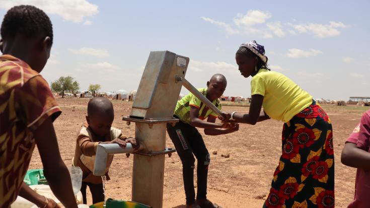 Salamata juntando agua con sus hijos en el campamento de Barsalogho, Burkina Faso