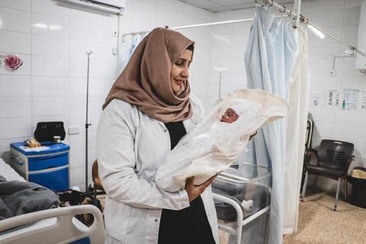 Rahma, supervisora ​​de parteras, sostiene a un recién nacido llamado Rivan.