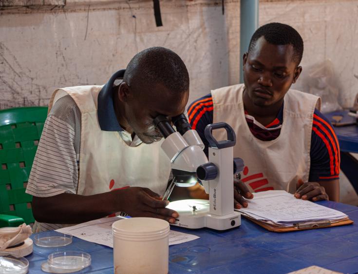 Julien Riyazimana (izquierda) y Paul Tuyininahaze (técnicos de control de vectores) examinan mosquitos bajo el microscopio, que fueron recolectados de las trampas para mosquitos instaladas en casas de diferentes zonas del campo de refugiados de Nduta. 