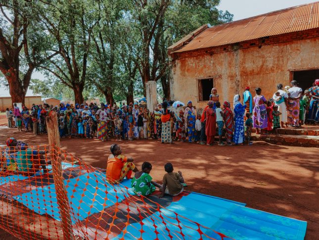 Mujeres, niñas y niños aguardan en el lanzamiento de nuestro campaña de inmunización en Ippy, el 4 de mayo de 2022. Esta campaña provee protección básica ante enfermedades como sarampión, polio, fiebre amarilla, meningitis y tuberculosis a aproximadamente 20.000 niñas y niños menores de 10 años, así como a 9.000 mujeres embarazadas.Khatab Muhy.