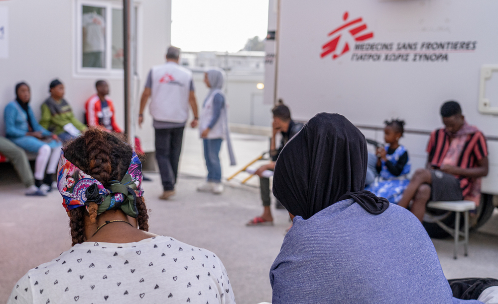 Nuestros y nuestras pacientes  pacientes en la sala de espera fuera de la clínica móvil en el Centro de Control de Acceso Cerrado de Zervou, Samos.
Allí prestamos servicios de atención primaria, incluida salud sexual y reproductiva. También contamos con un equipo de promoción de la salud que visita el campo para debatir y aplicar prácticas de higiene y asegurarse de que la población conoce el apoyo que nuestra organización puede prestar a los pacientes.MSF/Evgenia Chorou.