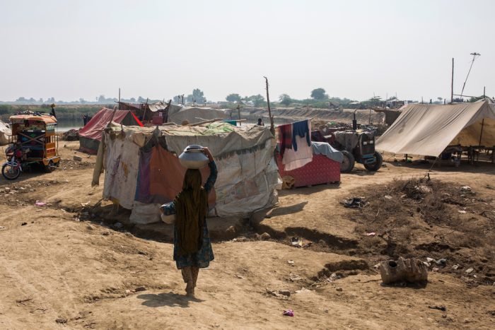 Imagen de archivo del 28 de octubre de 2022: una mujer lleva agua hacia su tienda en el campo para personas afectadas por las inundaciones en Sindh, Pakistán.Asim Hafeez.