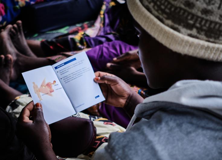 Paciente lee folleto sobre prevención de cáncer de cuello uterino en Malawi. 