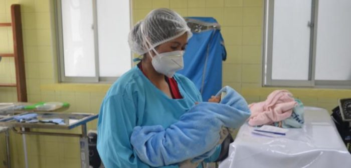 Una de nuestras enfermeras lleva en brazos un bebé recién nacido, para su primer control de peso y talla, en el Centro de Salud San Roque, de la ciudad de El Alto. Bolivia, abril de 2021Cecilia Rivero/MSF