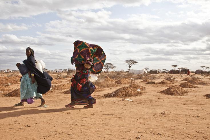 Dos mujeres refugiadas somalíes pasan junto a tumbas excavadas recientemente en el campo de refugiados de Dadaab.