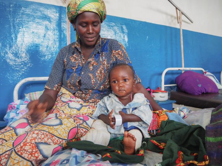 Bahati Maki Jospin, un niño de 15 meses de edad junto a su tía. Es la víctima más joven del ataque en la aldea de Jissa el 17 de mayo. El bebé estaba atado a la espalda de su madre cuando una bala los alcanzó, hiriendo su pierna y matando a su madre.