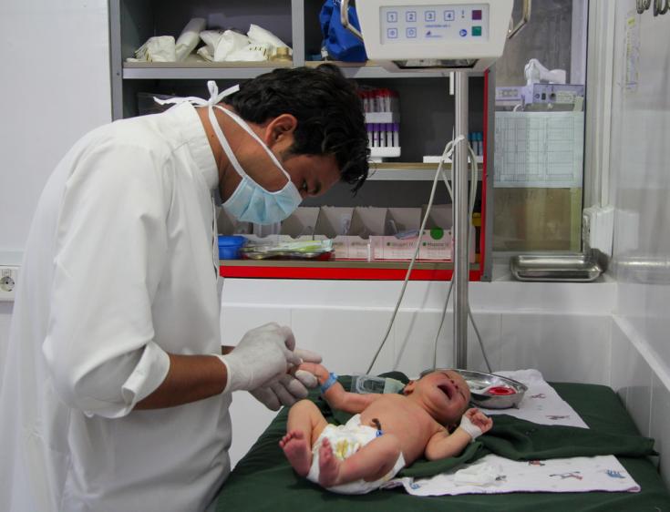 Un médico de Médicos Sin Fronteras inserta una cánula en la mano de un bebé para una transfusión intravenosa en la unidad de recién nacidos del hospital de la sede del distrito de Timergara, Pakistán.