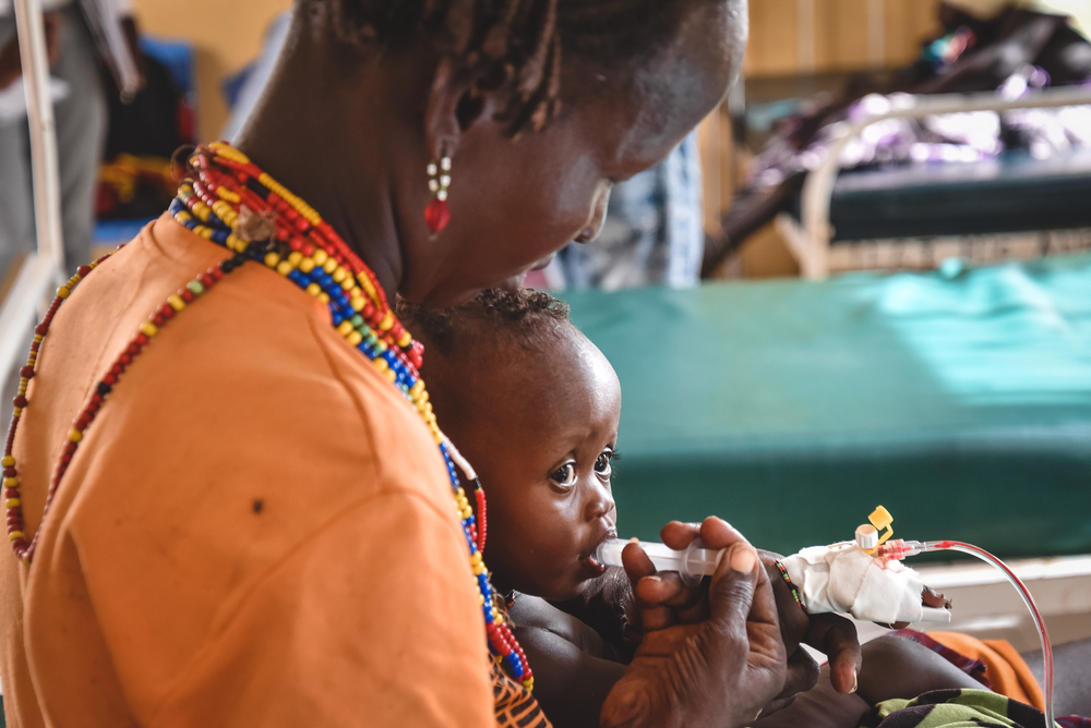 Guone Arbollo alimenta a Egura, su hija de nueve meses, con leche mediante una jeringa en el Centro de Salud de Illeret, Kenia. Egura sufre de severa malnutrición.
MSF/Lucy Makori.