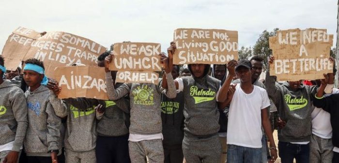 Migrantes sostienen carteles durante la visita de Antonio Guterres, el Secretario General de la ONU, a el centro de detención para migrantes Ain Zara, en Trípoli, la capital de Libia. 04 de abril de 2019.Mahmud Turkia/AFP
