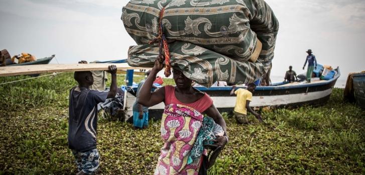 Una mujer desplazada interna procedente de República Democrática del Congo (RDC) lleva un colchón a la espera de embarcarse en un pequeño barco rumbo a la segura Uganda. (Marzo de 2018).John Wessels