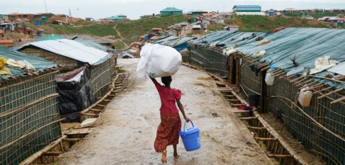 Una niña carga un balde de agua y otros artículos donados por la ONU a través de las calles mojadas del campamento de Balukhali. Los monzones causaron desastres en las comunidades locales, lo que provocó deslizamientos de tierra e incendios, lesiones, muertes y destrucción de infraestructura. Los suministros de agua se contaminaron, lo que es un riesgo para la salud pública. Dalila Mahdawi/MSF