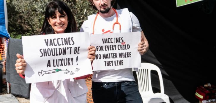 Corinne Peters y Stefanos Tsallas, parte de nuestro equipo de Médicos Sin Fronteras, sosteniendo carteles para pedir que la vacuna de la neumonía sea más accesible.MSF/Sophia Apostolia