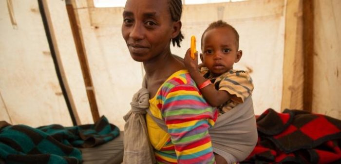 Una madre lleva a su hijo boca arriba en el centro de salud que apoyamos en Banko Gotiti, en el área de Gedeo, en el sur de Etiopía, donde el niño se está recuperando de la desnutrición.Igor Barbero/MSF