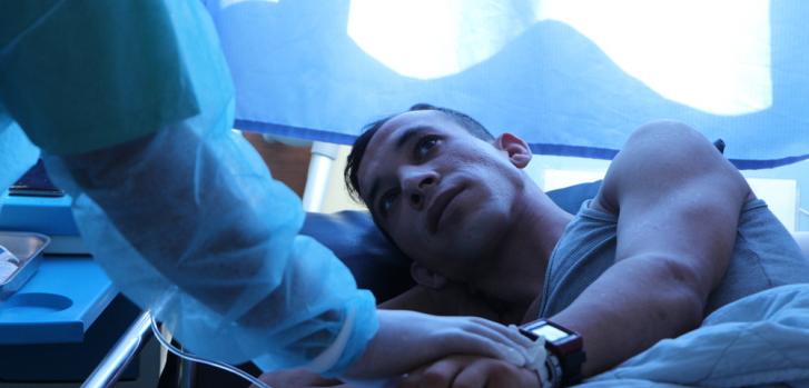 Ruslan, de 24 años, junto a una enfermera de Médicos Sin Fronteras en la habitación de aislamiento en un hospital en Khan Younis, Gaza. Está recibiendo tratamiento por una infección resistente a los antibióticos en los huesos de sus piernas, después recibir un disparo del ejército israelí durante una protesta.Jacob Burns/MSF